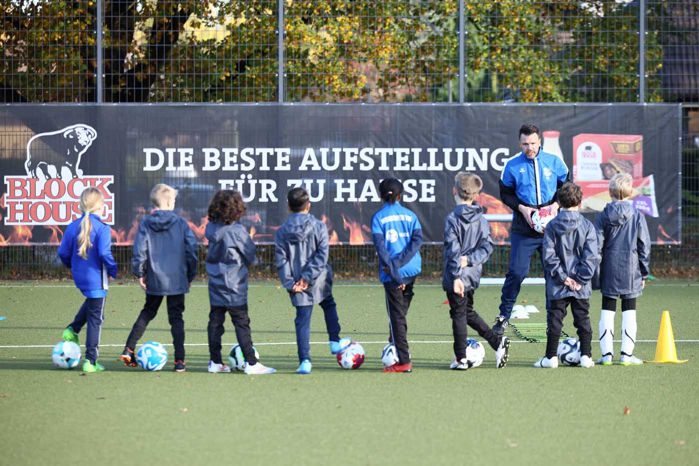 Ein Trainer des NTSV-Fußballcamps hat eine Gruppe von Teilnehmern um sich herum versammelt.